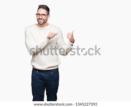 Young handsome man wearing glasses over isolated background Pointing to the back behind with hand and thumbs up, smiling confident