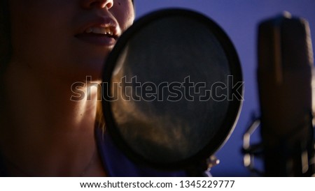 A young woman singing through the pop-filter