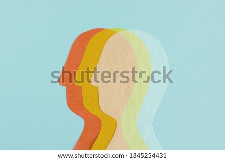Composed row of three transparent paper cutout of heads overlapped on blue background  Royalty-Free Stock Photo #1345254431