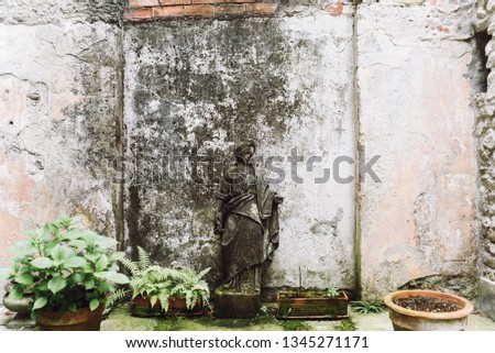 Dark old Greek statue stands in the garden