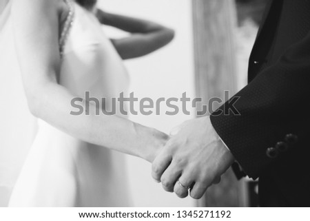 Bride and groom hold each other hands during the ceremony in church