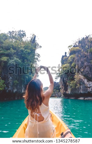 Cheerful enthusiastic Asian tourist girl taking photo when kayaking in Small Lagoon, one of the most popular destination for tourist in El Nido, Palawan Island, Philippines. Royalty-Free Stock Photo #1345278587