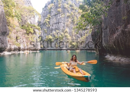 Cheerful enthusiastic Asian tourist girl taking photo when kayaking in Small Lagoon, one of the most popular destination for tourist in El Nido, Palawan Island, Philippines. Royalty-Free Stock Photo #1345278593