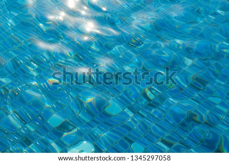 Blue and bright rippled water in swimming pool texture background