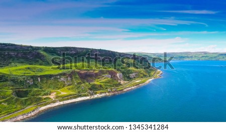 Amazing aerial shot of the blue sea and mountain in Cushendun the beautiful landscape view showing the greenish mountain with the small road fronting the blue sea