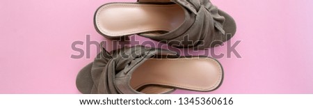 Top view of pair of mules/clogs (military green color) on pink background