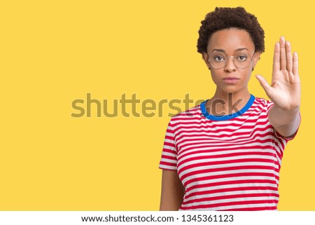 Beautiful young african american woman wearing glasses over isolated background doing stop sing with palm of the hand. Warning expression with negative and serious gesture on the face.