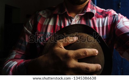 young man in red plaid shirt holding a typical Brazilian Northeast hat Royalty-Free Stock Photo #1345386638