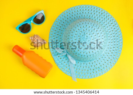 summer accessories. beach accessories. sunscreen, hat and glasses on a bright yellow background. top view.