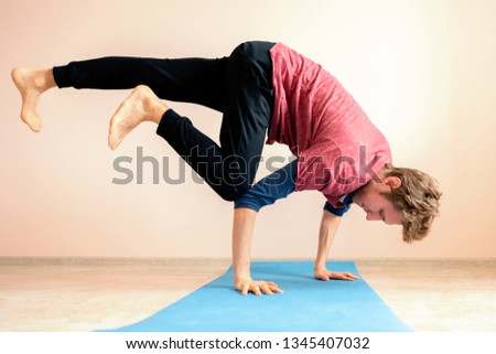young man doing very difficult advanced yoga asana position balance