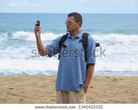 A man on the beach with a smartphone. Atlantic ocean background.