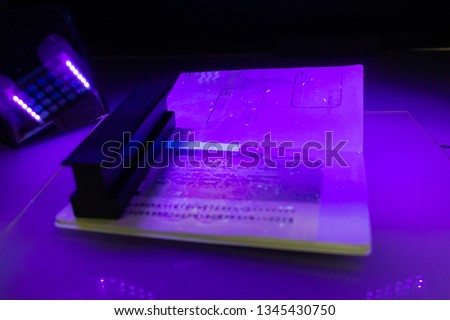 Process of the passport visa checking, close-up. The study of protective elements of the document in ultraviolet light. High security printing for for visa stickers. Passport protection against fraud Royalty-Free Stock Photo #1345430750