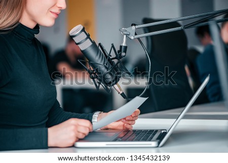 Young woman recording a podcast in a studio, close-up.