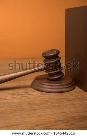 close up of brown book in leather cover and gavel on wooden table isolated on orange