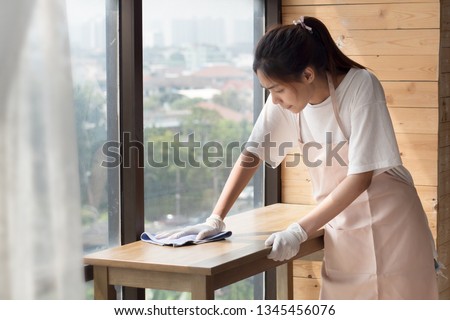 woman cleaner cleaning, disinfecting with disinfectant living room in apartment. portrait of asian woman cleaning staff doing housekeeping or domestic helper job. young adult asian woman model Royalty-Free Stock Photo #1345456076