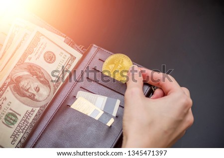 Golden bitcoin and hundred dollar bills in leather wallet. Bitcoin with dollar in purse. Profit from mining cryptocurrencies. Business, commercial. Photo with flare