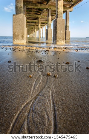 Sea tide and a sandy beach below pier view on a sunny summer day in Felixstowe, UK