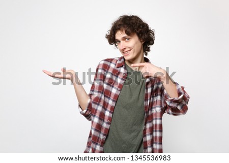 Portrait of smiling young man in casual clothes looking camera pointing hand, index finger aside isolated on white background in studio. People sincere emotions, lifestyle concept. Mock up copy space