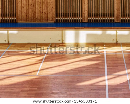 Schooll gym hall with water heating system hidden over wooden bars cover.  Basketball court. Lines of playfield in hall.