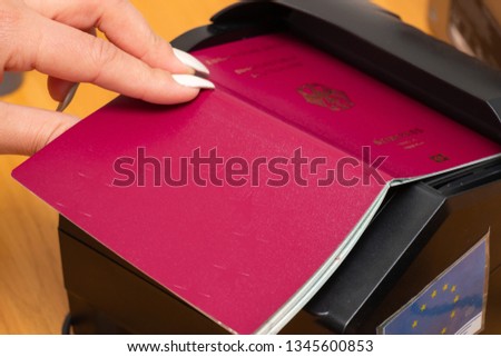 The process of scanning a German biometric passport to register the fact of crossing the state border. Female hand puts a passport to the scanning device. Concept of overseas travel, immigration Royalty-Free Stock Photo #1345600853
