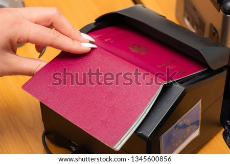 The process of scanning a German biometric passport to register the fact of crossing the state border. Female hand puts a passport to the scanning device. Concept of overseas travel, immigration Royalty-Free Stock Photo #1345600856
