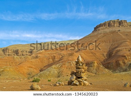 Picturesque red clay mountains in desert. Cairn (pile of stones) as landmark for tourists. Altyn-Emel National Park. Almaty, Kazakhstan