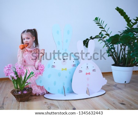 Easter 2019 Beautiful little girl in a dress with Easter decorations. Big Easter bunnies. A lot of different colorful Easter decor. Multicolored decor