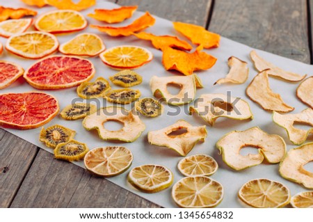 Mixed dried fruits and vegetables slices on wooden background