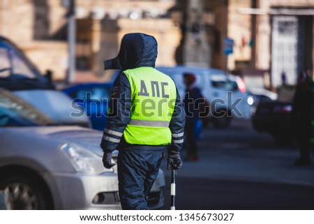 Russian Inspector of traffic police highway patrol regulates the movement of transport in the center of Moscow, in yellow vest jacket with a sign "DPS - Traffic Patrol Police"