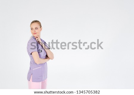 Woman doctor blonde young light gray background studio day beautiful one looking with a smile to the side. Good mood.Copy space right.