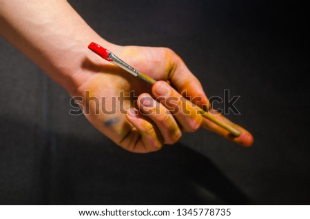 artist holding paintbrush with red gouache color on the black background concept. Be creative and draw. Painting background. 