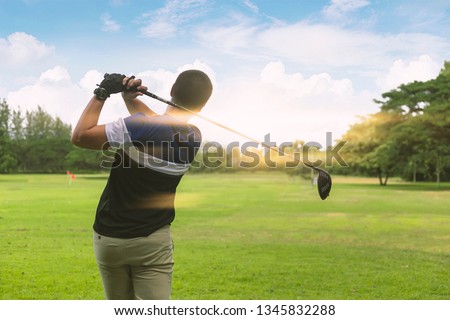 Close up Golfer is driving golf ball to green course with light flare.
