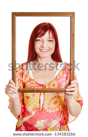 Woman looking through empty wooden picture frame