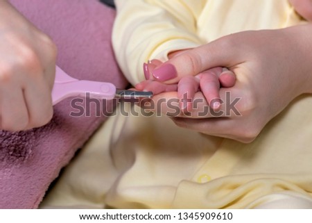 Mother cuts 
her small child fingernails with protected scissors. Close-up. 