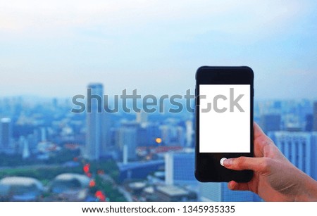 Person holding a smartphone with white screen with a blurry city view