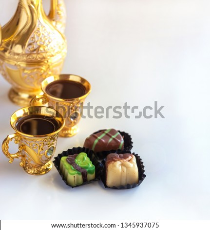 Still life with traditional golden arabic coffee set with dallah, cup and chocolate candy. White background. Selective focus. Copy space.