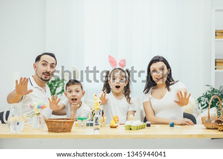 Emotional easter family sitting at the table extending their hands forward, showing stop sign. Open mouthes, expressiveness on their faces.