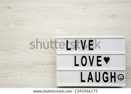 "Live Love Laugh' words on lightbox over white wooden surface, top view. Flat lay, overhead, from above. Copy space.
