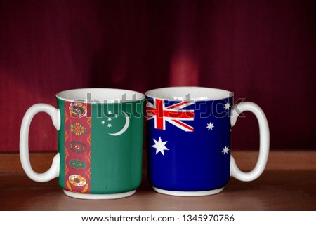Australia and Turkmenistan flag on two cups with blurry background
