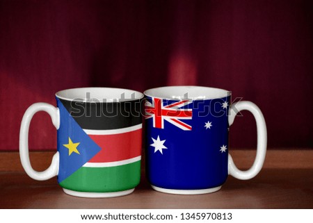 Australia and South Sudan flag on two cups with blurry background