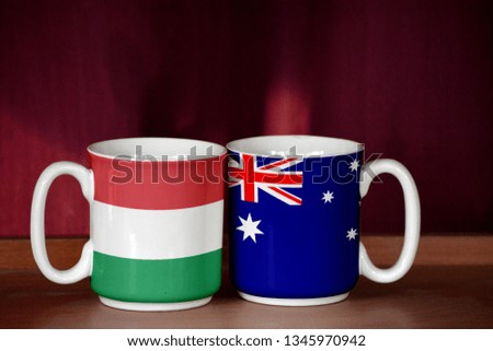 Australia and Hungary flag on two cups with blurry background