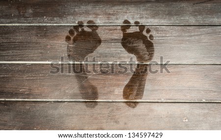 Wet human footprints on dark wooden plank floor. Walk from beach to hotel or home. Abstract backgrounds and wallpapers. Holidays and vacations in summer.
