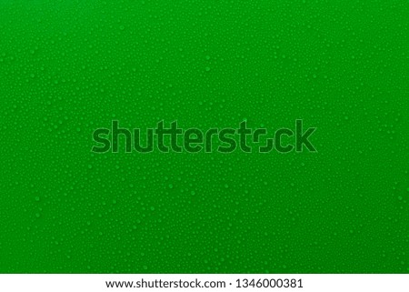 Small droplets of water on a green, matte background illuminated with a delicate light.