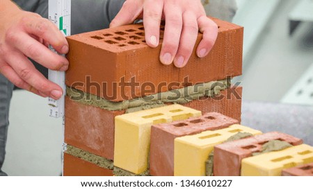 Piling up of bricks using the cement to paste the worker uses a ruler to make sure the bricks are aligned to each other