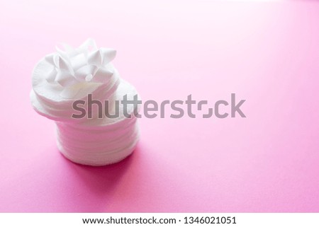 Clean white cotton stack of disk for beauty face hygiene with selective focus on pink neutral background. Cosmetic softness pure sponge for makeup remover. Sterile cleanliness facial sponges