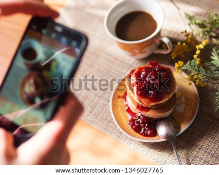 Women's hands take pictures of Japanese pancakes with jam