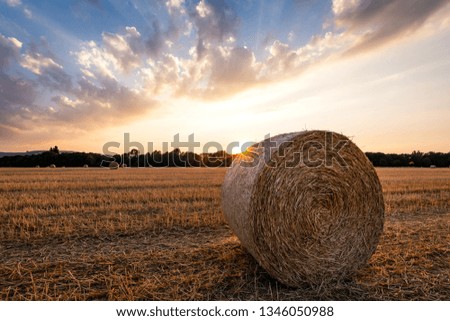 Sunset on a field of Straw after the harvest, with bales of Straw in the foreground