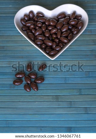 Nuts arranged in heart shape on background. Food image close up candy, chocolate milk, extra dark almond nuts. Love Texture