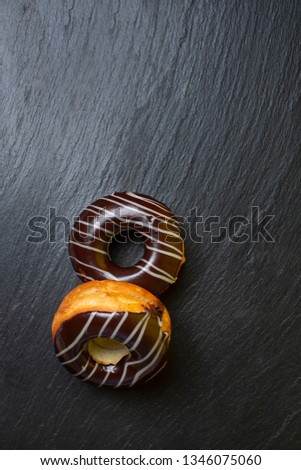 two donut in chocolate on a stone plate background and space for your advertising on it.close-up.Collection for celebration design.Sweet dessert