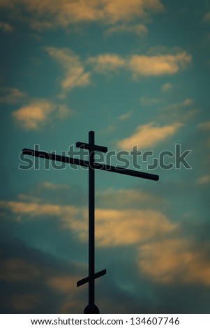 Church cross with sunset sky in the background.